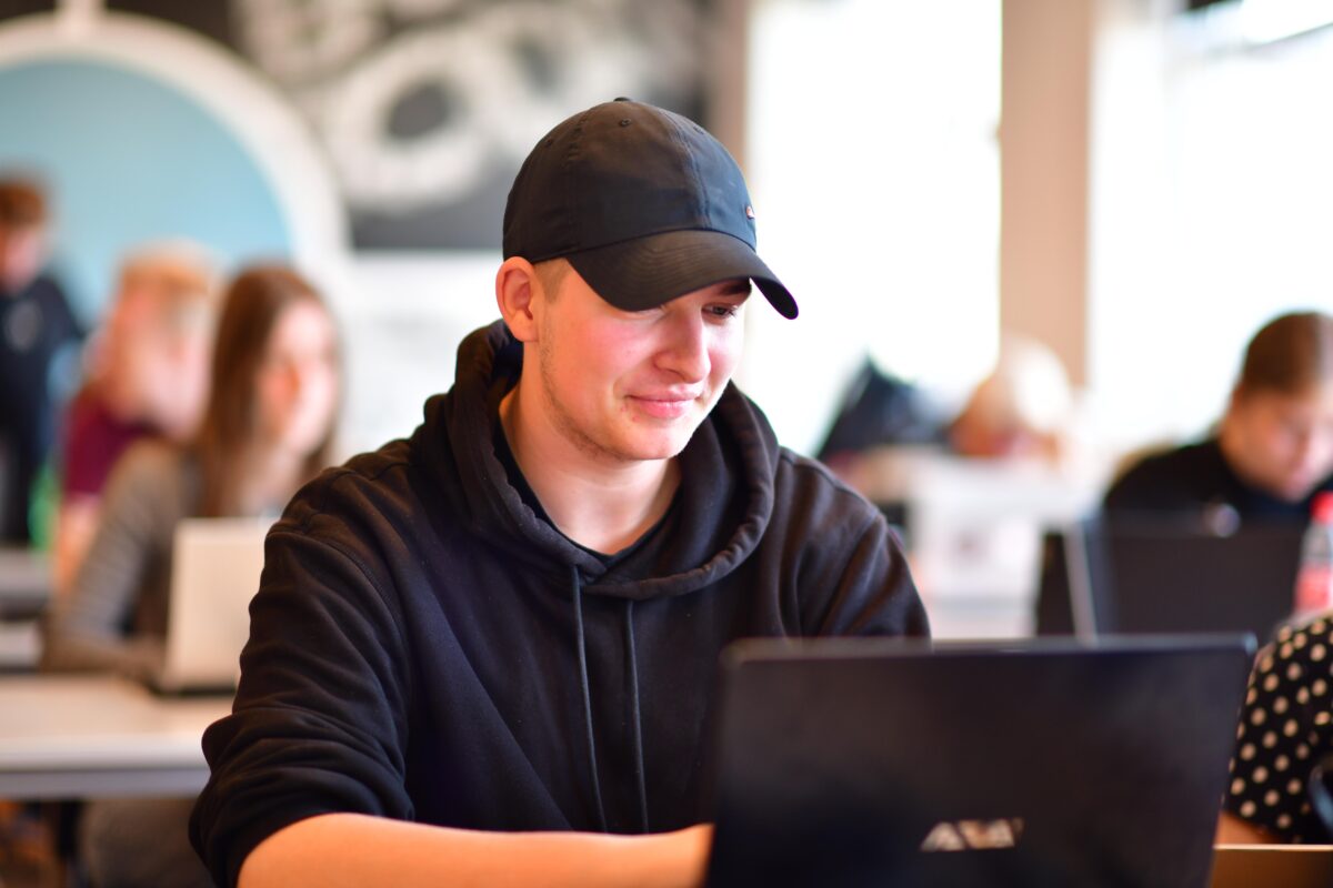 Ung studerende med kasket, der sidder ved sin pc